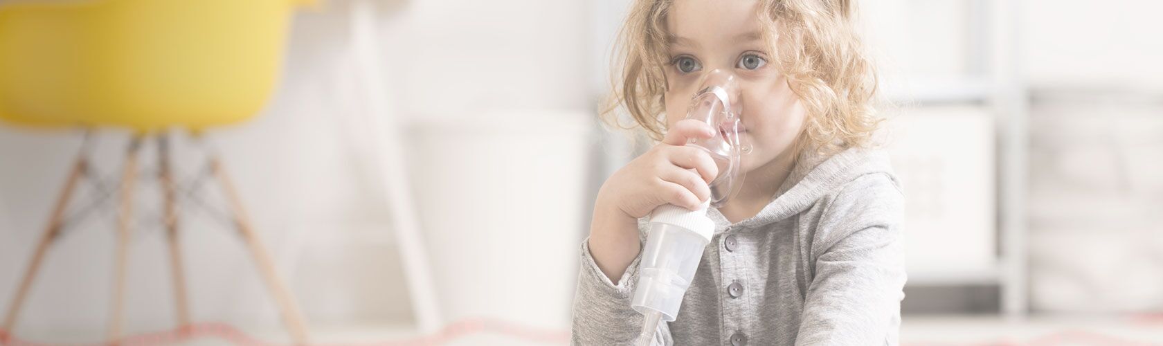 Ein Kind benutzt ein Inhalationsgerät in einem hellen Raum, um seine Atemwege zu unterstützen.